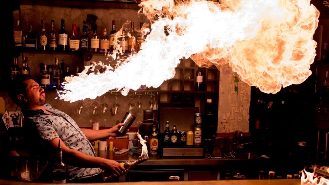 A fire breather sending a jet of flame across the back bar