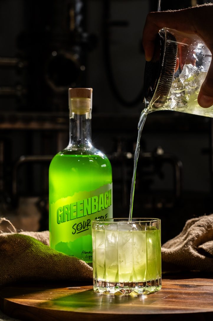 The Greenbach sour apple bottle in its pink world